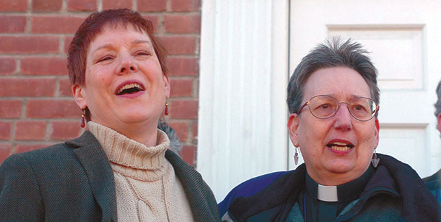 Ministers Dawn Sangrey ’93 (left) and Kay Greenleaf lead a crowd of supporters in a hymn in front of New Paltz, NY, courthouse on March 22, 2004. Later, they were arraigned on criminal charges for officiating over same-sex weddings. Photo by Tim Roske, AP