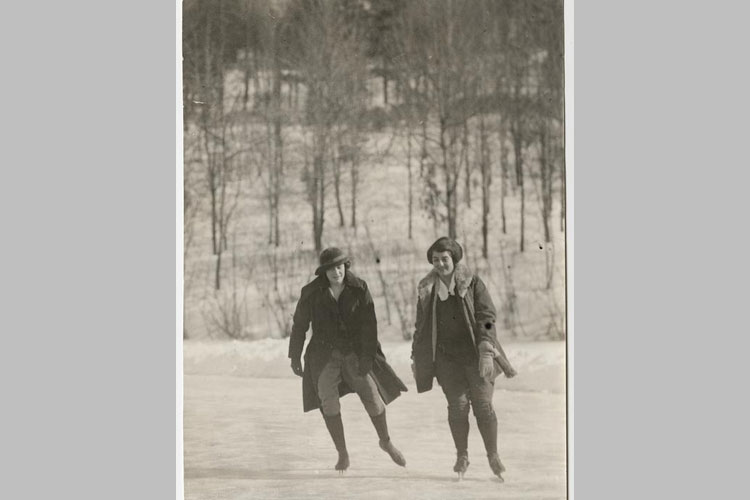 Mary P. Bruyn, class of 1924 and Winifred A. Sanders, class of 1924, skate on Lower Lake with Prospect Hill in the background.