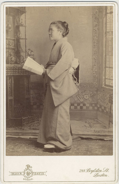 Full-length portrait of Toshi Miyagawa, class of 1893, in Japanese dress, holding book. 