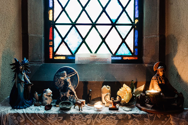 Statues of Pagan icons and others are placed on a lace cloth in a windowsill