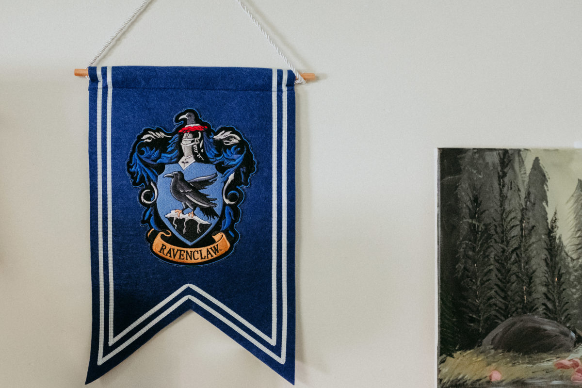 A close-up of a Ravenclaw pennant in a student's room. To the right is part of a painting of a woodland scene.
