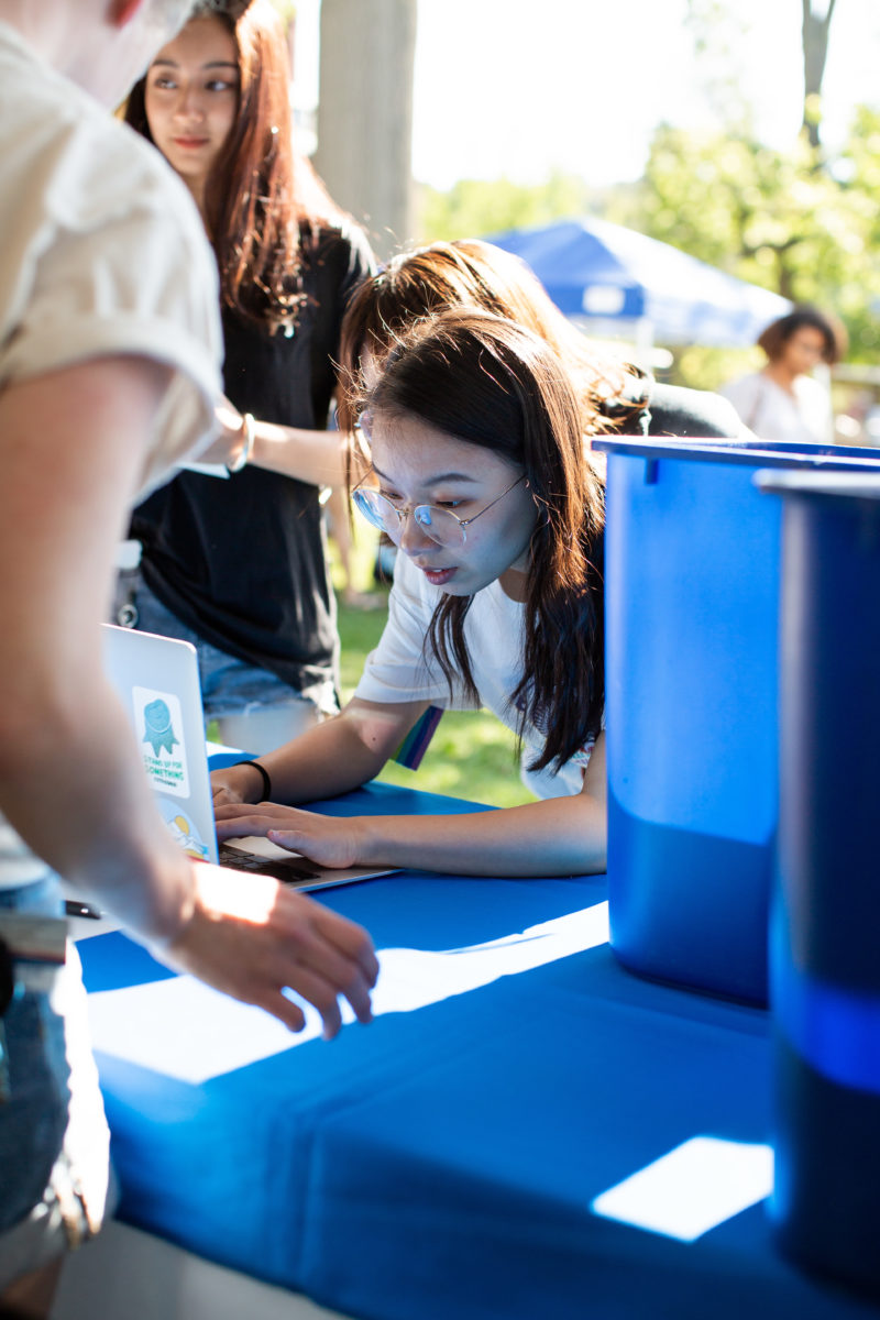 A student leans over a computer to check out a recycling bin at the Orientation welcome tent.